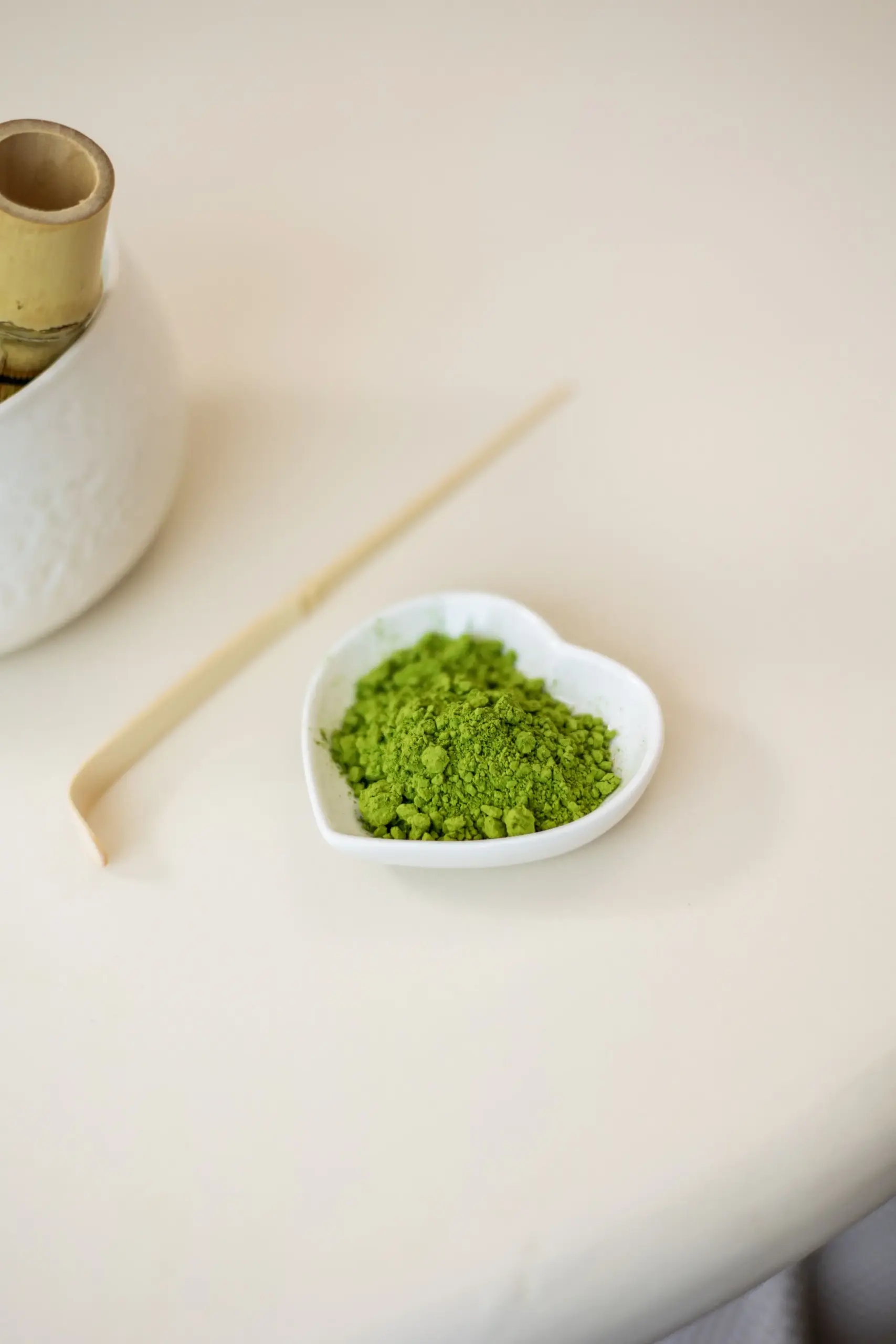 SHINYU Matcha - Single pack (30gr) 5 Bright green matcha powder in a small heart-shaped white dish, with a bamboo whisk and scoop nearby