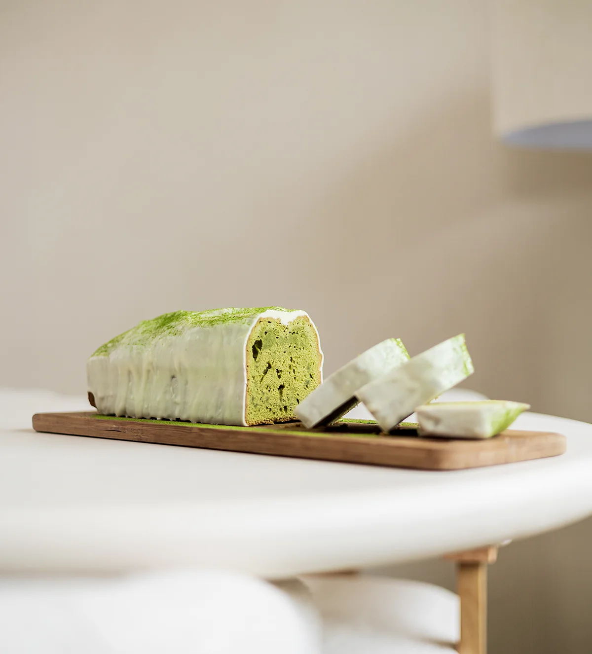 Gesneden matcha cakereep met witte glazuur op een houten snijplank