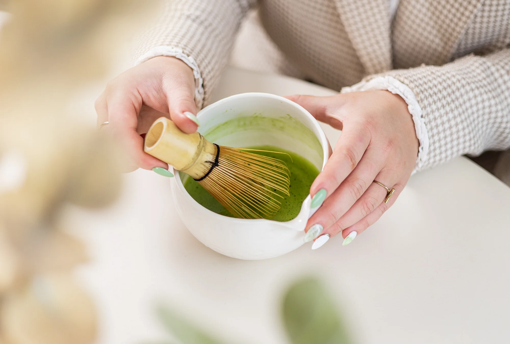 SHINYU Matcha starter kit 6 Vrouw klopt matcha thee met een bamboeklopper in een witte kom