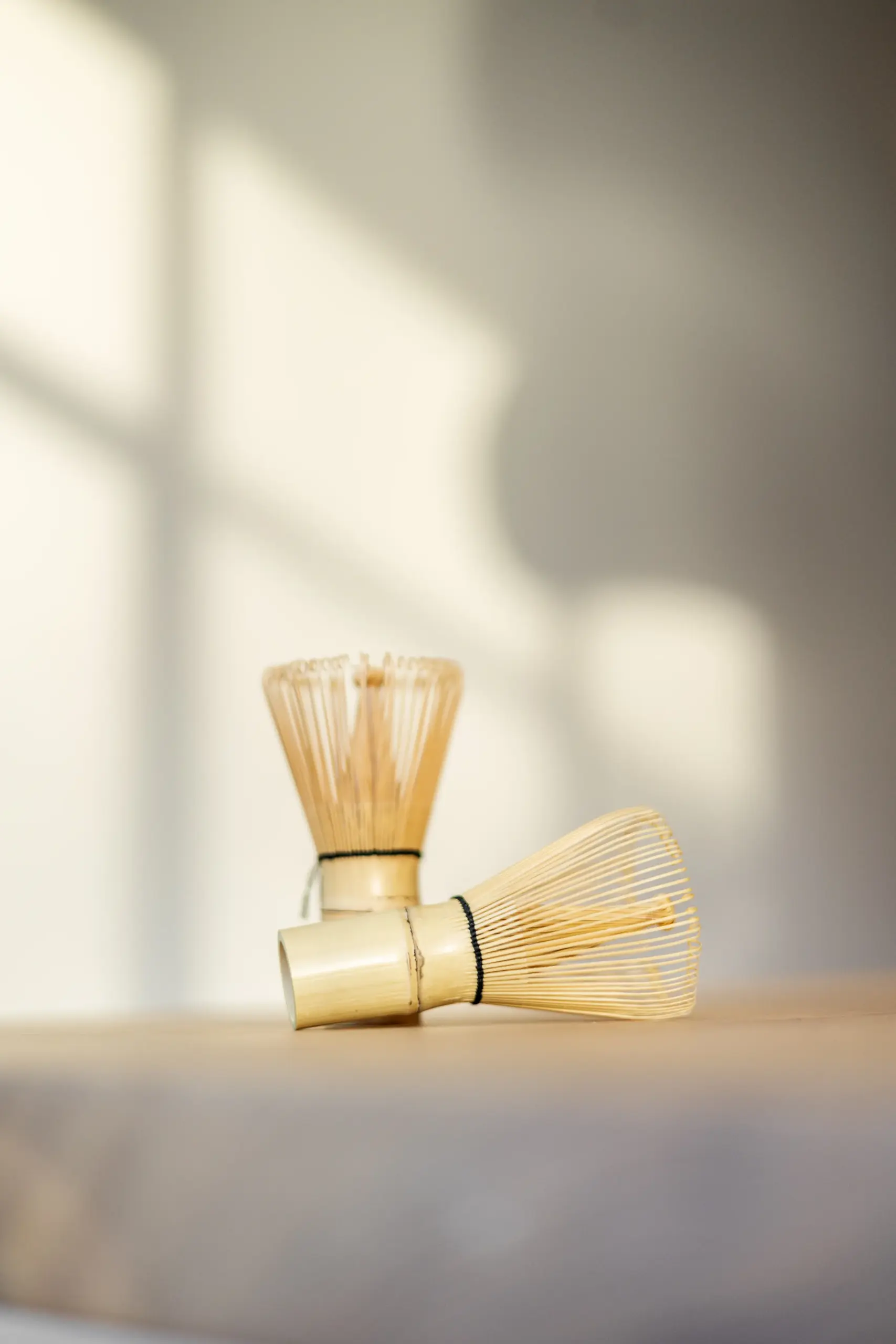 SHINYU Matcha starter kit 2 Twee bamboe matcha-kloppers op een licht oppervlak in zacht natuurlijk licht