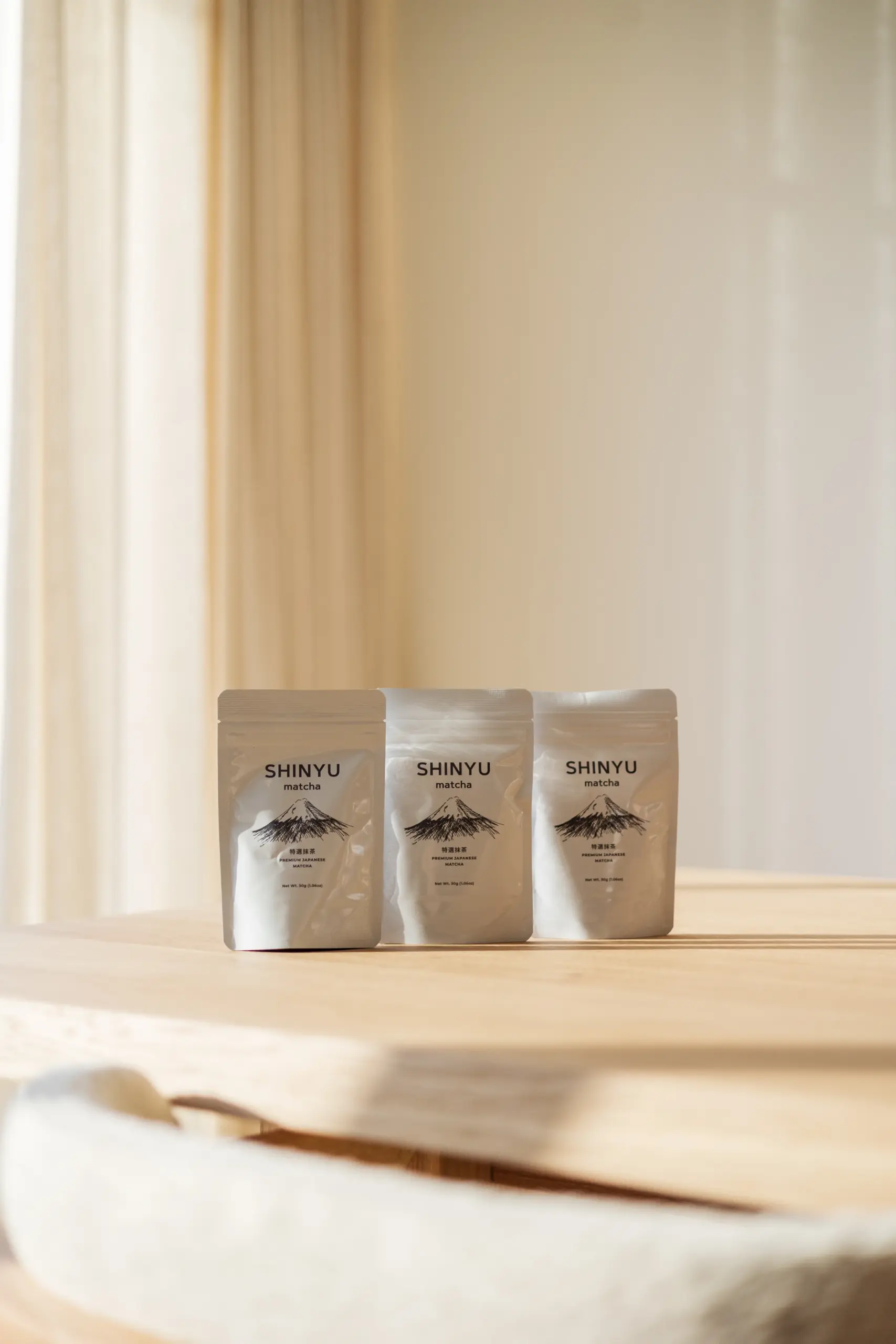 De Stay Fresh Bundel (triple pack + lepel + bewaarblik) 4 Drie zakjes Shinyu Matcha Premium Japanese Matcha op een houten tafel