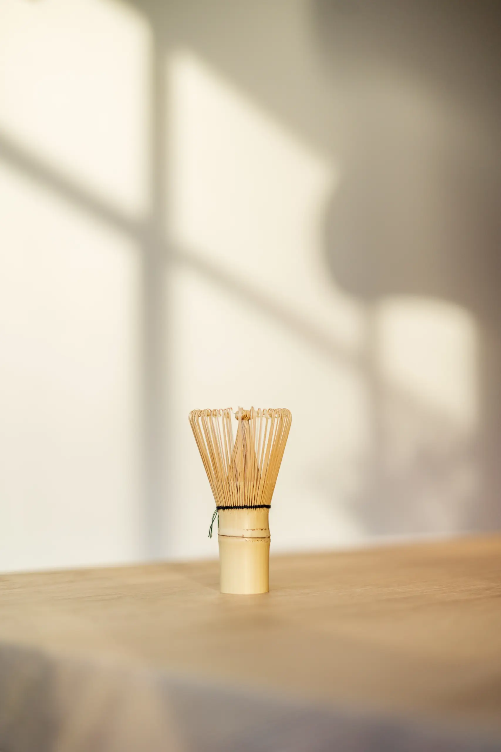 Voordeelbundel (triple pack matcha + whisk + lepel) 3 Bamboe matcha-garde (chasen) staat rechtop op een houten tafel in zacht zonlicht
